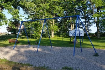 swingset in a park with lots of trees